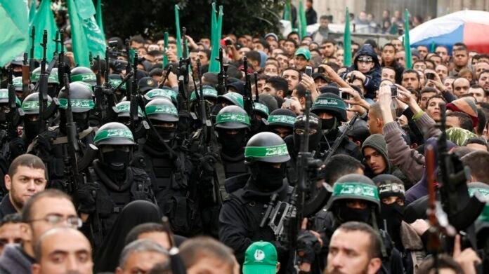 People watch as Palestinian members of al-Qassam Brigades take part in a military parade in Gaza City
